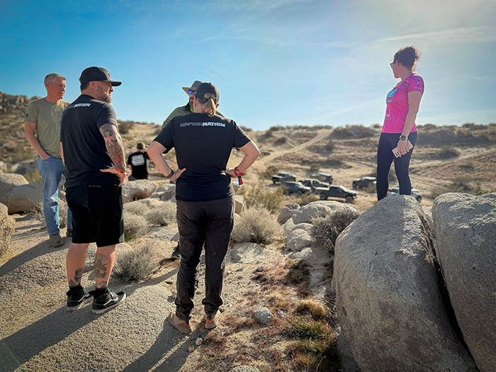 Group of people standing on a rocky desert landscape with clear blue sky.